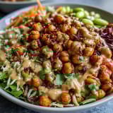A colorful Peanut Chickpea Protein Bowl features fluffy quinoa, crunchy cabbage, and tender roasted chickpeas, ready to enjoy with a zesty lime wedge.  