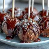 Graduation cake pops in school colors topped with shimmering gold sprinkles, perfect for celebrating academic achievements.