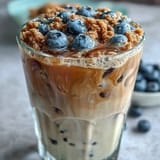 Sweet, frothy blueberry muffin iced coffee with vanilla cold foam, ready to sip.