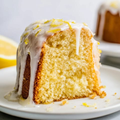 Golden-brown Lemon Pound Cake with a thick lemon glaze dripping down the sides, perfect for dessert. 