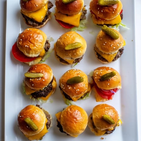 Perfectly toasted mini slider buns hold juicy beef patties with melted cheddar, tangy pickles, and fresh lettuce.