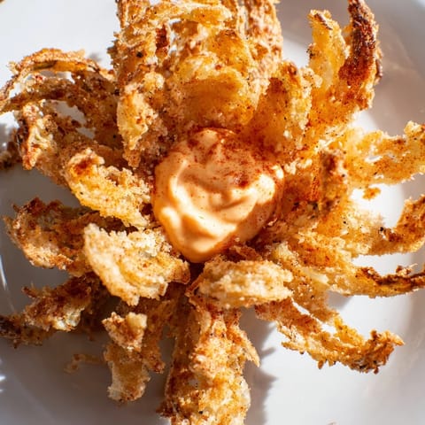 Thick-cut Onion Petals coated in a crunchy, paprika-speckled batter, served alongside a creamy, zesty spicy dipping sauce.