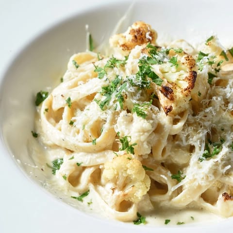 Golden roasted cauliflower florets and garlic cloves on a baking sheet before blending into a creamy Roasted Cauliflower Alfredo sauce.