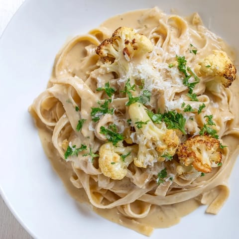 Tossing freshly cooked fettuccine with the silky homemade Roasted Cauliflower Alfredo sauce in a large skillet.