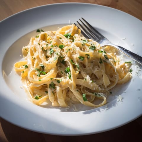 A close-up of Sriracha Honey Pasta twirled on a fork, glistening with creamy sauce and flecked with fresh parsley.