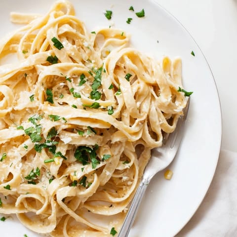 Platter of Sriracha Honey Pasta topped with parsley and parmesan, with garlic and honey notes highlighted for serving.