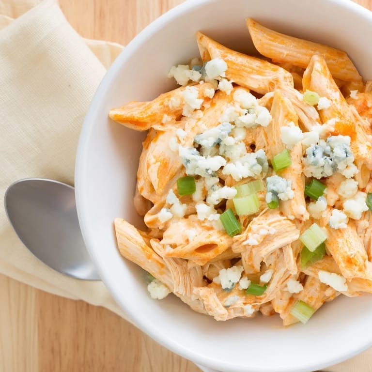 This plated Buffalo Chicken Pasta dish features tender rotini pasta tossed in a rich, spicy buffalo cream sauce with shredded chicken, mozzarella, and blue cheese crumbs, perfect for a cozy weeknight dinner.