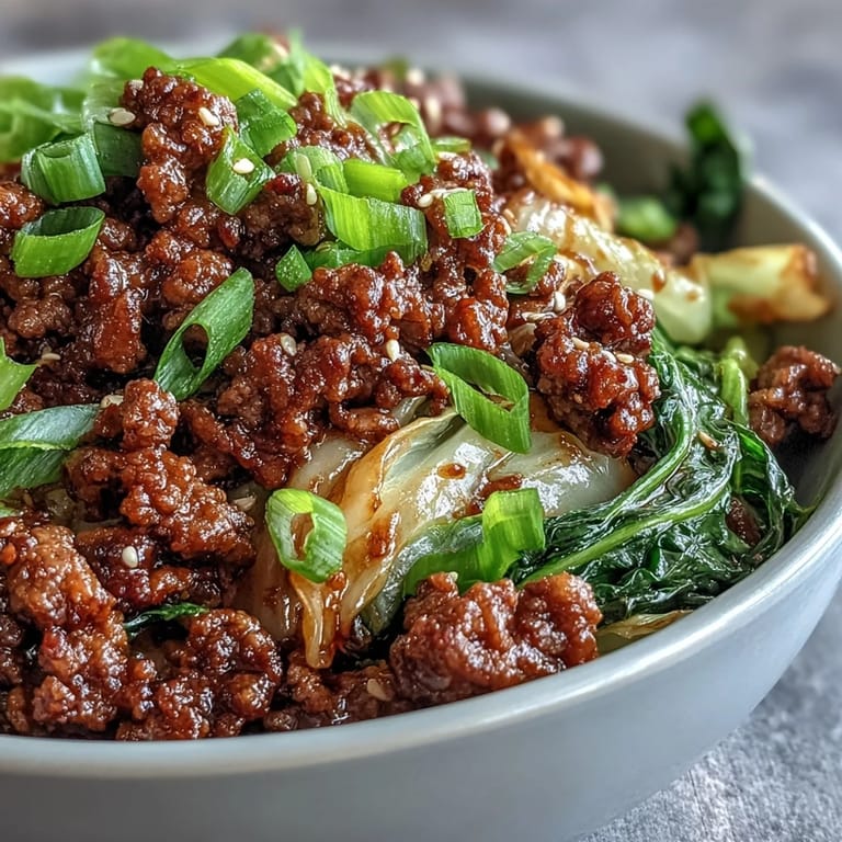 Chinese Ground Beef and Cabbage Stir-Fry served in a white bowl, garnished with green onions and sesame seeds.