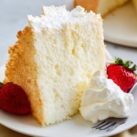 Light, airy Angel Food Cake dusted with powdered sugar on a plate.