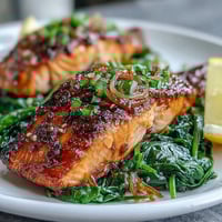 Glistening miso salmon atop a vibrant bed of wilted spinach.