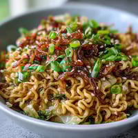 Close-up of Fried Cabbage Ramen in a wok, featuring golden, crisp-edged cabbage and noodles glistening with savory sesame sauce.