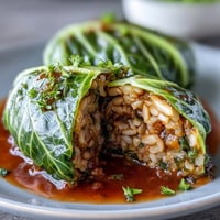 Tender cabbage leaves stuffed with lentils and brown rice, smothered in a rich tomato sauce in this Baked Vegan Cabbage Rolls recipe.