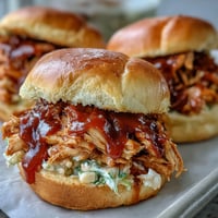 Juicy pulled BBQ chicken piled high on toasted buns, topped with creamy coleslaw for a classic summer sandwich.